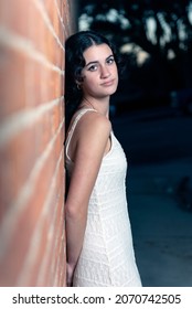 Confident High School Senior Girl Leaning Her Back Against Contemporary Brick As Sunset Settles Over The Downtown Area Of Ventura.