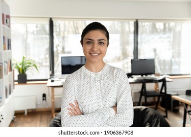 Confident Indian Millennial Businesswoman Posing With Hands Folded In Office. Head Shot Portrait Of Happy Young Female Professional, Business Leader, Boss Or Corporate Coach Looking At Camera.