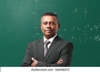 Confident Indian Teacher Standing Near Blackboard