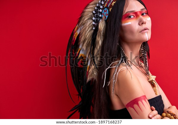 confident\
indigenous woman in shamanic wear looking at camera isolated over\
red background, mystical indian female in studio. people\
individuality, diversity, ethnicity\
concept
