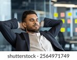 Confident Latin American businessman taking a moment to relax in a workplace, showcasing calmness and professionalism after hard work in the modern corporate world.