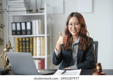 Confident lawyer in cozy office, showing agreement with thumbs up, surrounded by legal paperwork and laptop, exuding professionalism and success
