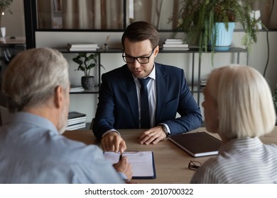 Confident lawyer, real estate agent, financial advisor giving consultation to mature couple of clients, explaining legal documents, helping to paper form, contract, agreement for signing.