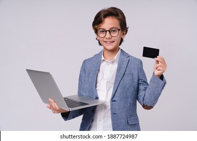 Confident little boy in formal attire holding credit card and laptop isolated over grey background - Powered by Shutterstock