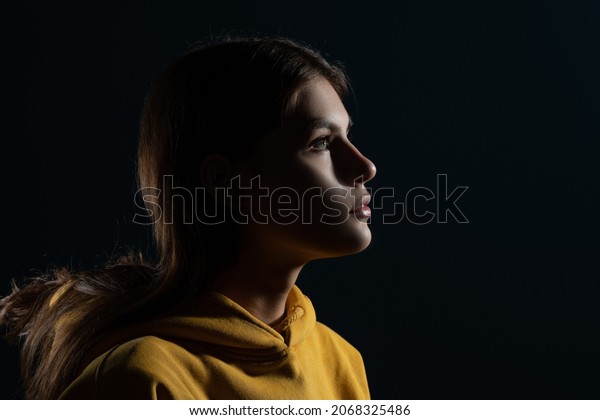 Confident look ahead, concept. A young Caucasian\
woman, side view of the illuminated silhouette of the head, looks\
to the right. The mysteries of the subconscious, the brain and the\
mind