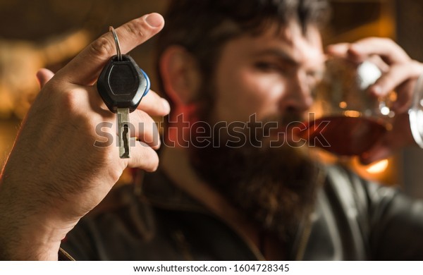Confident macho\
man drinking whiskey and holding his car keys. Luxury lifestyle of\
successful young businessman. Handsome bearded businessman is\
drinking expensive\
whiskey