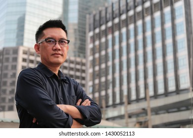 Confident male business executive  with arms crossed standing in front of office building background - Shutterstock ID 1430052113