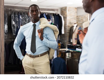 Confident Male Customer Choosing Fashion Beige Suit In Mens Store. High Quality Photo