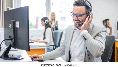 Confident male customer support operator with headset working in call center