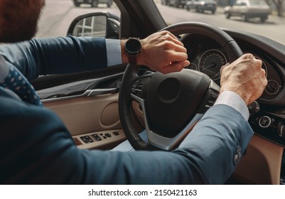 Confident male entrepreneur wearing suit driving a car while looking at his watch - Powered by Shutterstock