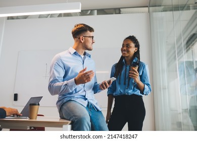 Confident male and female colleagues in smart casual clothes discussing smartphone mobility in workspace enjoying corporate friendship, happy partners talking about office networking via cellphone - Shutterstock ID 2147418247