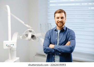 Confident male patient of stomatology standing in modern clinic. Man smiling at the camera crossing his arms in front of him. - Powered by Shutterstock