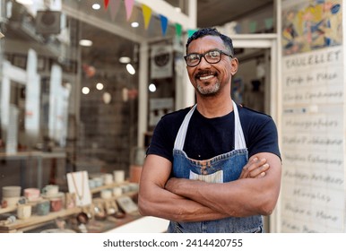 Confident male potter with arms crossed standing outside ceramic shop - Powered by Shutterstock