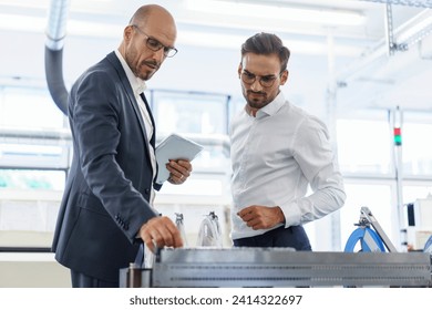 Confident male professionals discussing over machinery against machinery at factory - Powered by Shutterstock