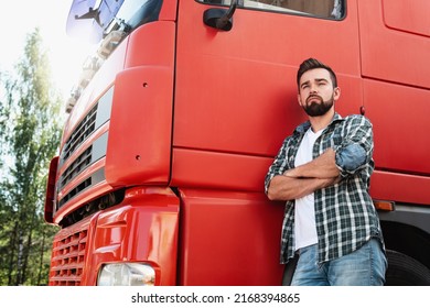 Confident Male Truck Driver Standing Beside His Red Cargo Truck 