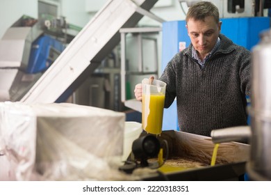 Confident male worker controlling quality of olive oil of traditional cold pressing on artisanal olive oil factory - Powered by Shutterstock