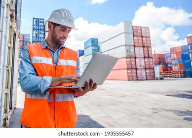 Confident Man Engineer Wearing White Safety Helmet Using Computer Laptop And Check For Control Loading Containers Box From Cargo Freight Ship For Import And Export, Transport