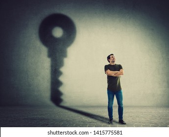 Confident Man, Keeps Arms Crossed, Casting A Key Shadow On The Wall. Ambition And Business Success Concept. Motivation And Inner Strength Symbol.