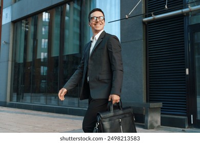 Confident man in a suit and glasses walking with a briefcase in an urban environment.

 - Powered by Shutterstock