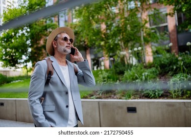 Confident Man Wearing Straw Hat And Backpack Talking On Phone, Businessman In Casual Clothes In Summer On The Way To Work.