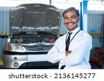 Confident manager or supervisor at car garage standing with crossed arms by looking at camera - concpet of successful occupation, career and businessman