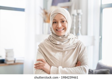 Confident mature Middle Eastern muslim islamic woman in hijab, mother, tutor, wife standing with arms crossed at home. Front view portrait of a arabian woman