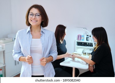 Confident Mature Woman Beauty Salon Owner Taking Care Of Body With Hands Nails. Smiling Female Looking At The Camera, Manicure Process Background