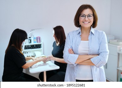 Confident Mature Woman Beauty Salon Owner Taking Care Of Body With Hands Nails. Smiling Female Looking At The Camera, Manicure Process Background