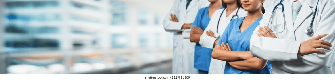 Confident medical staff team with doctor nurse and healthcare specialist professions people in blurry hospital corridor background. Medical and healthcare community in panoramic banner. Neoteric - Powered by Shutterstock