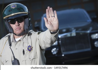 Confident Middle Aged Traffic Cop Signaling Stop Gesture With Car In Background
