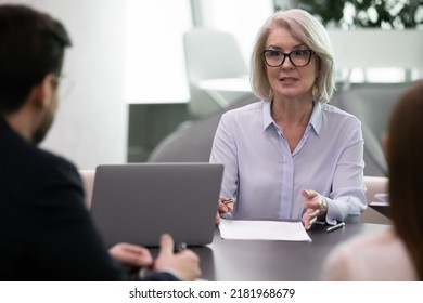 Confident Middle-aged Caucasian Businesswoman Talk With Colleagues Or Clients At Office Meeting. Successful Mature Female Leader Or Boss Lead Head Briefing With Business Partners. Leadership Concept.