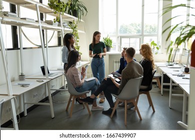 Confident Millennial Businesswoman Stand Lead Multiracial Team Meeting In Modern Coworking Office, Successful Female Leader Talk Brainstorm With Diverse Colleagues, Cooperate At Briefing At Workplace