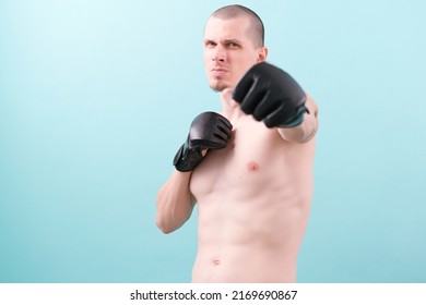 A confident MMA fighter in black gloves ready to fight on a blue background. Fighting stance. Pose. Gloves. Hero. Powerful. Endurance. Fighting. Combat. Conflict. Instruction. Punching. Box. Knockout