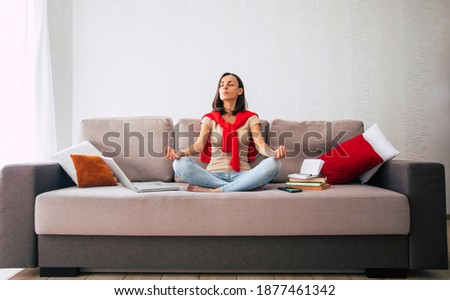 Confident modern cute young woman is online working and relaxing at home on the couch with her laptop on the freelance job