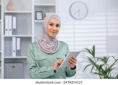 Confident Muslim woman in a modern office setting, using a digital tablet to perform business tasks. Professional and tech-savvy. - Powered by Shutterstock