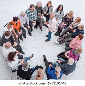 Confident Older Woman Standing In A Circle Of Like-minded People