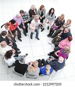 Confident Older Woman Standing In A Circle Of Like-minded People