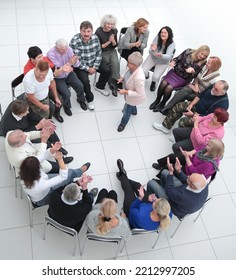 Confident Older Woman Standing In A Circle Of Like-minded People