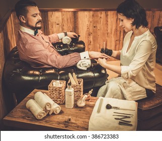 Confident Old-fashioned Man Doing Male Manicure In A Barber Shop. 