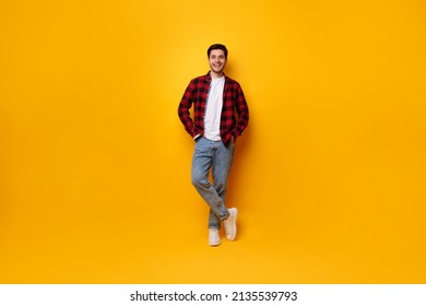 Confident Person. Portrait Of Cheerful Casual Man Posing Standing Isolated Over Yellow Studio Background Leaning On Wall Holding Hands In Pockets, Smiling Looking At Camera, Full Body Length Banner