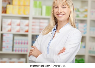 confident pharmacist standing with crossed arms in pharmacy