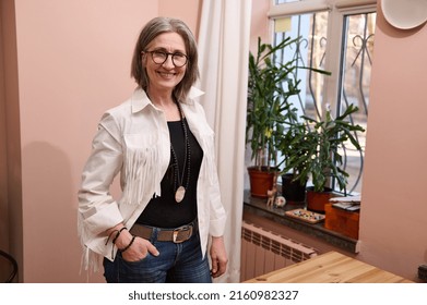 Confident portrait of a smiling stylish elegant 60 years old, elderly European woman, fashion designer, tailor, dressmaker in her own fashion tailor atelier - Shutterstock ID 2160982327