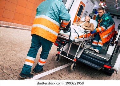Confident and professional doctors unloading an ill patient from an ambulance car on a stretcher near the hospital building