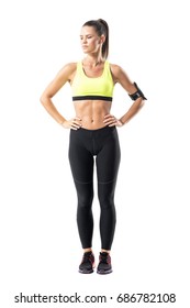 Confident Proud Athletic Sporty Female Jogger With Hands On Waist Looking Down. Full Body Length Portrait Isolated On White Background.