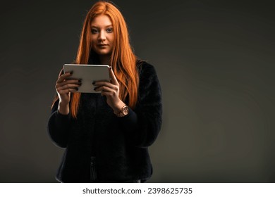 Confident redhead entrepreneur uses a tablet to manage her innovative business ventures