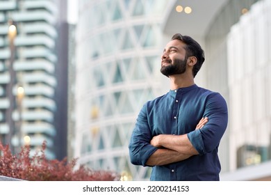 Confident rich eastern indian business man executive standing in modern big city looking and dreaming of future business success, thinking of new goals, business vision and leadership concept. - Powered by Shutterstock