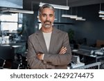 Confident rich middle aged older professional business man, smiling mature executive ceo manager, older male entrepreneur successful lawyer standing arms crossed in office looking at camera, portrait.