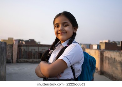 Confident rural Indian school girl standing with backpack