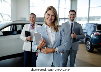 Confident salesteam in dealership, three beautiful consultants or managers in elegant suit looking on camera. - Powered by Shutterstock