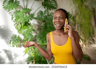 Confident satisfied African American woman florist talking on phone, surrounded by mini garden of flowers and plants. Black female takes plant order in flower shop, businesswoman, small business - Powered by Shutterstock